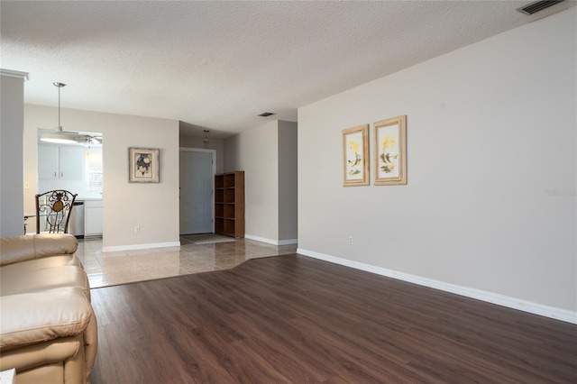 unfurnished living room featuring a textured ceiling, ceiling fan, and wood-type flooring