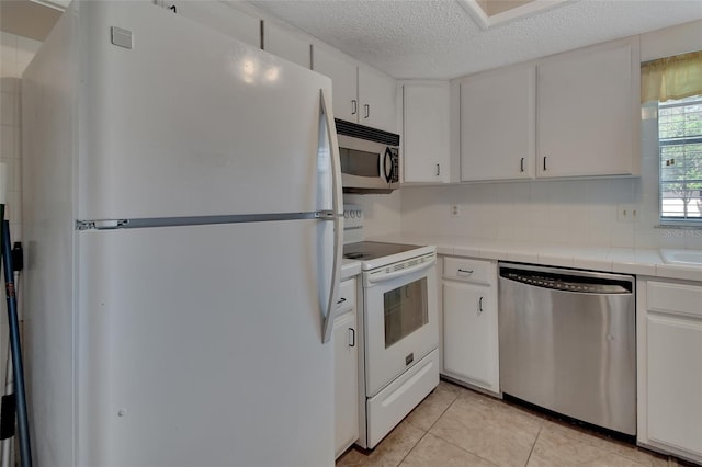 kitchen with white cabinetry, appliances with stainless steel finishes, a textured ceiling, tile counters, and light tile patterned floors