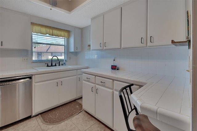 kitchen featuring sink, white cabinetry, dishwasher, and tile counters