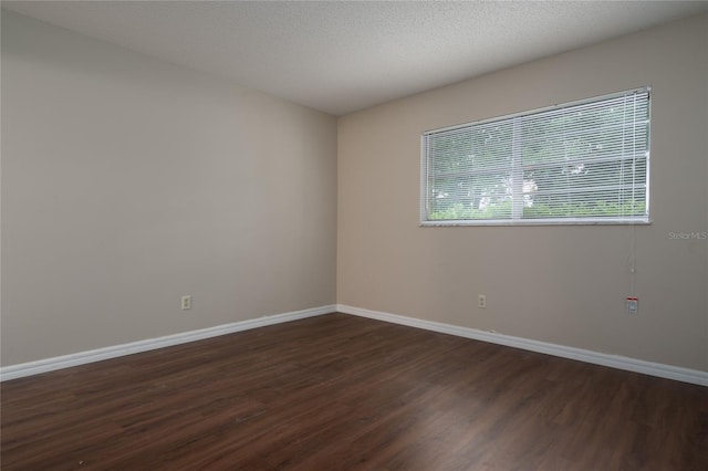 unfurnished room with dark wood-type flooring and a textured ceiling