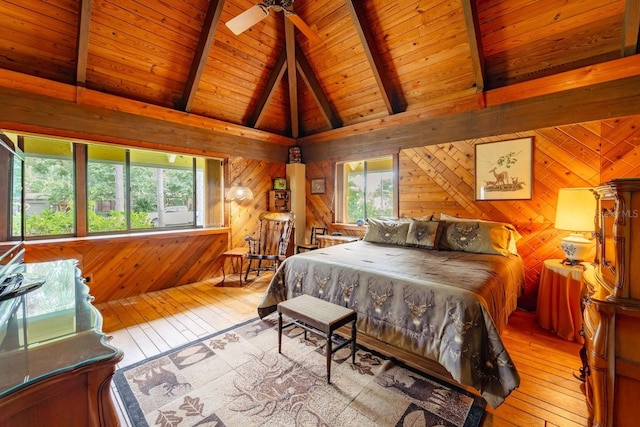 bedroom with light hardwood / wood-style floors, wooden walls, and multiple windows