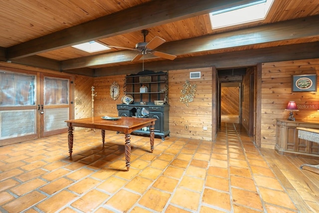 office area with a skylight, wooden walls, and ceiling fan