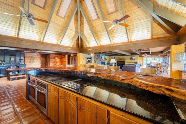 kitchen featuring beam ceiling, stainless steel oven, high vaulted ceiling, and black stovetop