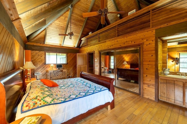 bedroom featuring beam ceiling, wooden ceiling, high vaulted ceiling, wood walls, and light wood-type flooring