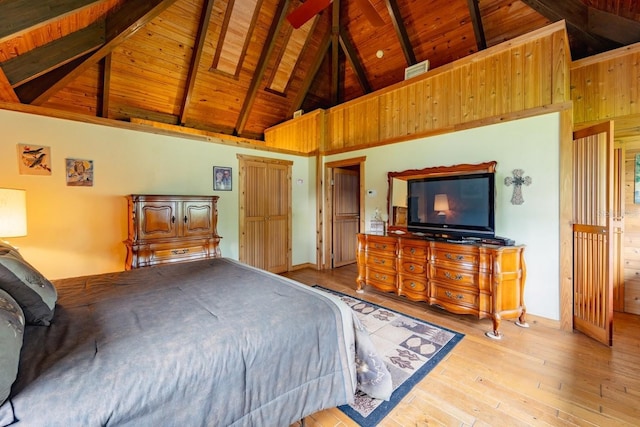 bedroom with beamed ceiling, light wood-type flooring, high vaulted ceiling, and a skylight