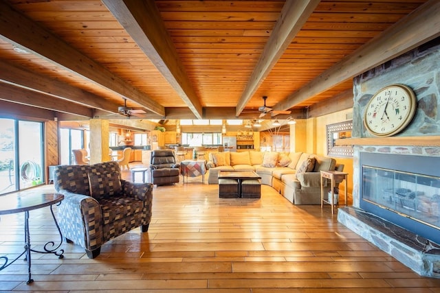 living room with beam ceiling, a wealth of natural light, and light wood-type flooring