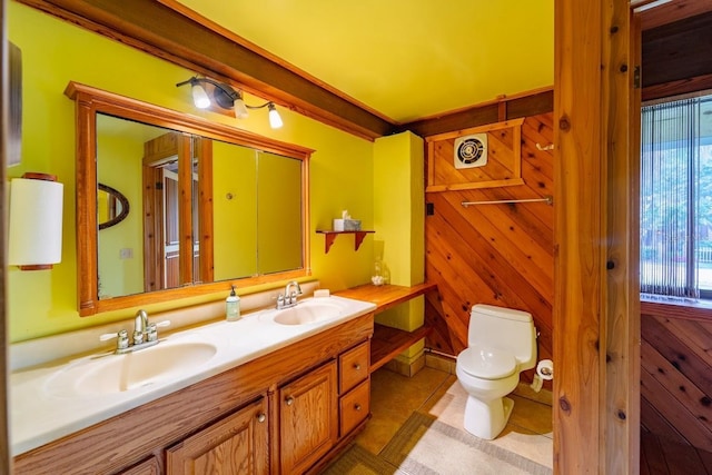 bathroom with tile patterned floors, wooden walls, vanity, and toilet