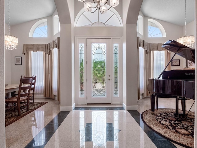 foyer featuring plenty of natural light, tile flooring, high vaulted ceiling, and a chandelier