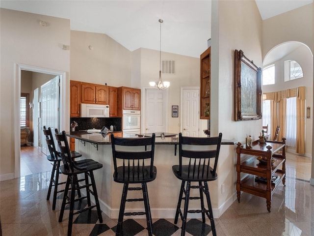 kitchen with a kitchen breakfast bar, plenty of natural light, white appliances, and tasteful backsplash