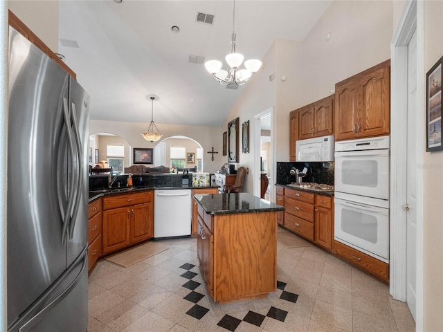 kitchen featuring white appliances, an inviting chandelier, a kitchen island, light tile floors, and hanging light fixtures