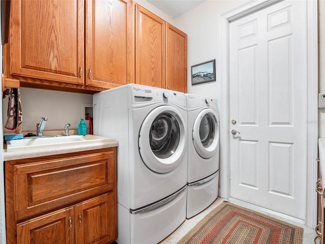 clothes washing area with washer and dryer, cabinets, sink, and hookup for a washing machine