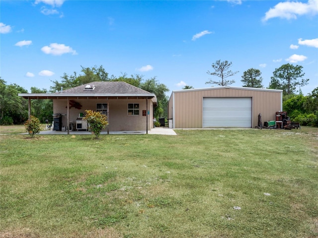 back of house featuring a garage, a yard, and an outdoor structure