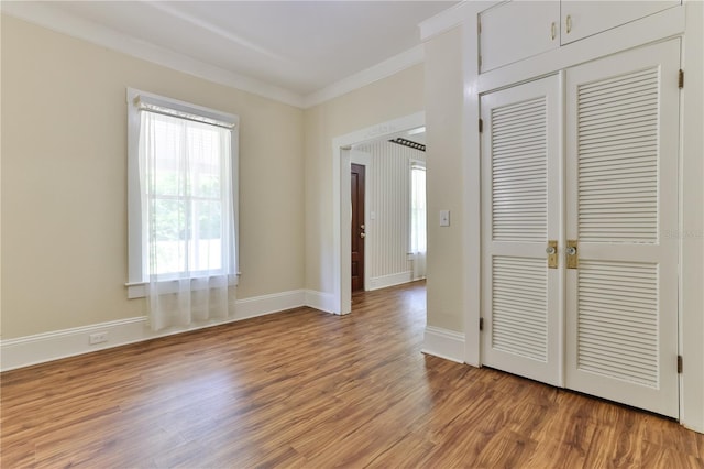 unfurnished bedroom with a closet, ornamental molding, and light wood-type flooring