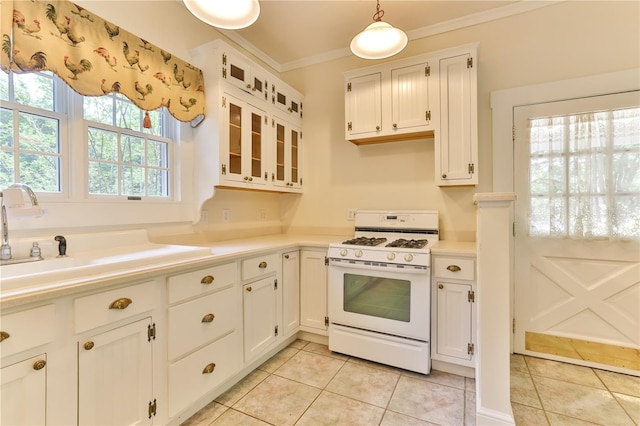 kitchen with white range with gas cooktop, crown molding, pendant lighting, light tile patterned floors, and white cabinets