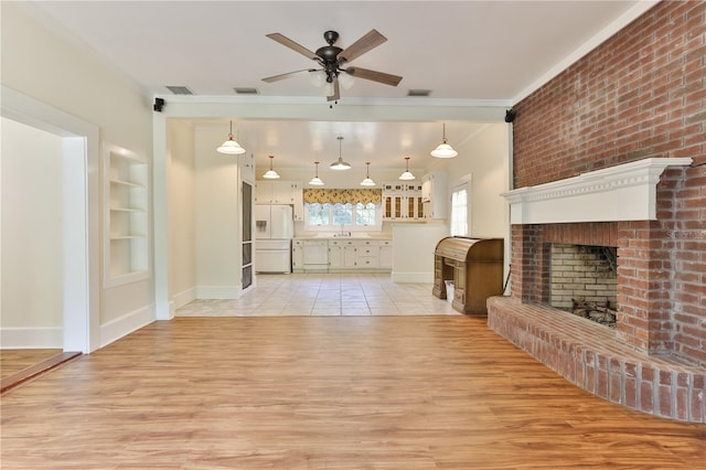 living room with a brick fireplace, ornamental molding, ceiling fan, built in features, and light hardwood / wood-style floors