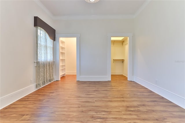 unfurnished bedroom featuring a walk in closet, a closet, and light hardwood / wood-style floors