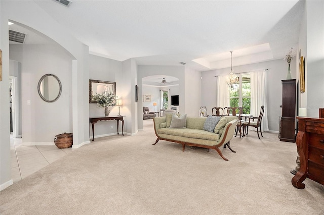 living room featuring a notable chandelier, a tray ceiling, and light tile flooring