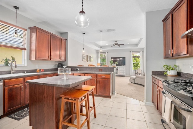 kitchen with ceiling fan, a tray ceiling, light tile flooring, and appliances with stainless steel finishes