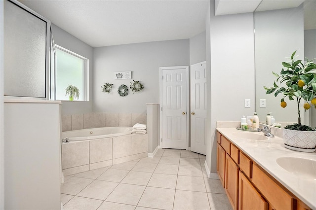 bathroom with tiled bath, vanity with extensive cabinet space, double sink, and tile flooring