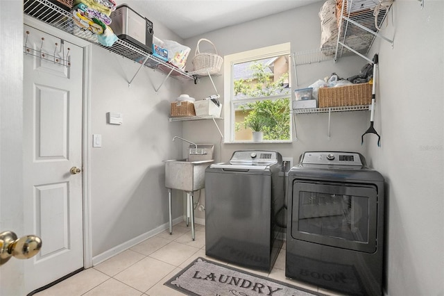 laundry area featuring sink, light tile floors, and washing machine and dryer