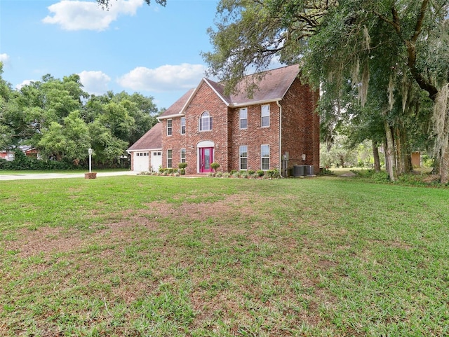 colonial house featuring central air condition unit, a front yard, and a garage