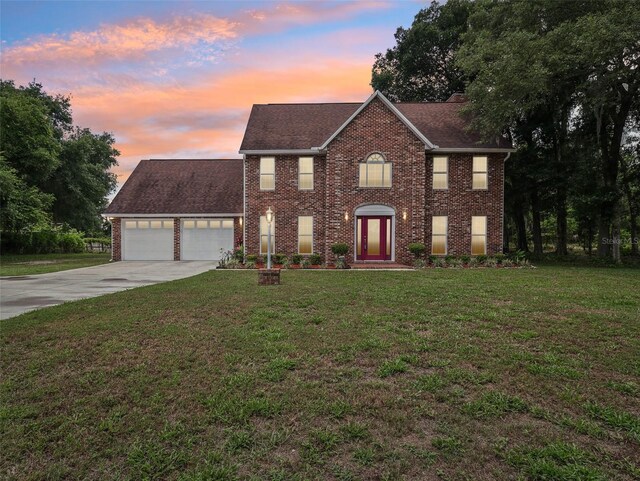 colonial house featuring a lawn and a garage