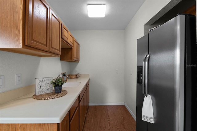 kitchen featuring dark hardwood / wood-style flooring, sink, and stainless steel refrigerator with ice dispenser