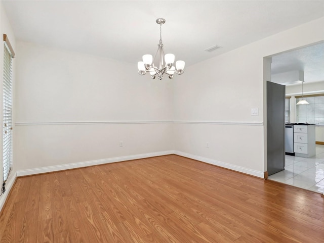 unfurnished room with a chandelier, light hardwood / wood-style floors, and a healthy amount of sunlight