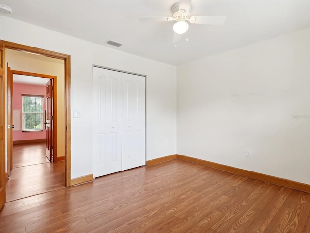 unfurnished bedroom featuring ceiling fan, light wood-type flooring, and a closet