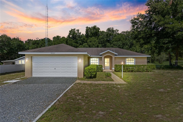 single story home featuring a garage and a yard