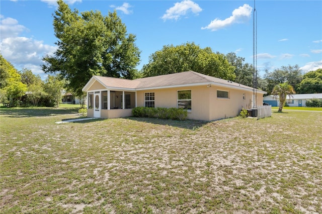 back of property featuring a sunroom, a yard, and central AC unit