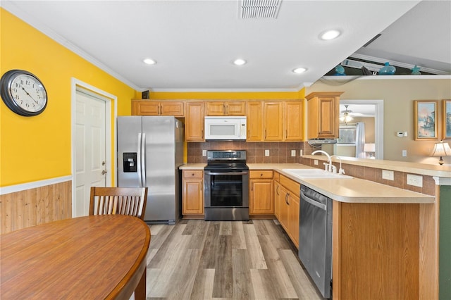 kitchen featuring light hardwood / wood-style floors, stainless steel appliances, kitchen peninsula, backsplash, and sink