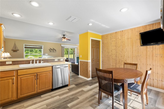 kitchen with crown molding, sink, light hardwood / wood-style flooring, and stainless steel dishwasher