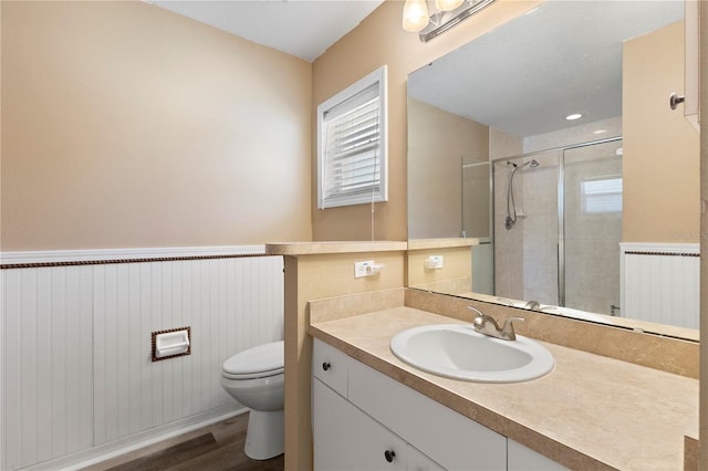 bathroom featuring walk in shower, wood-type flooring, vanity, and toilet