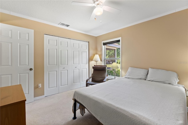 carpeted bedroom featuring crown molding, a closet, and ceiling fan