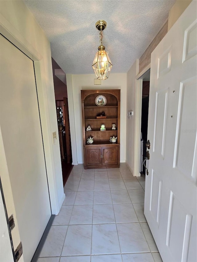 corridor with a textured ceiling and light tile floors