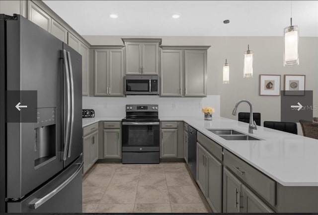 kitchen with kitchen peninsula, gray cabinetry, stainless steel appliances, sink, and decorative light fixtures