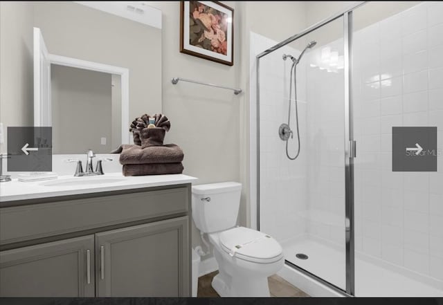 bathroom with vanity, a shower with shower door, and toilet