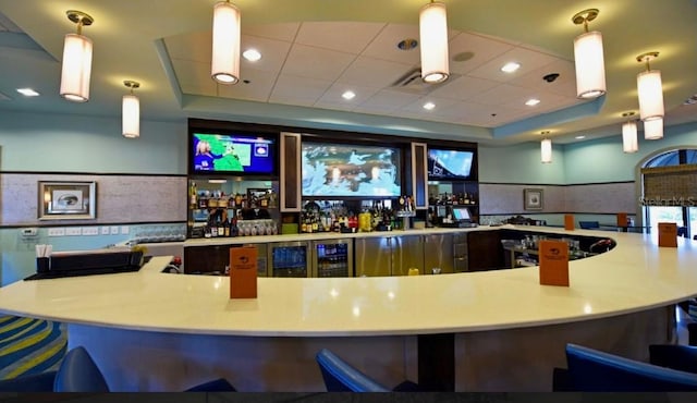 bar featuring a raised ceiling, a paneled ceiling, beverage cooler, and pendant lighting