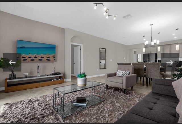 505 Ocean Course Ave Unit 505, Davenport, FL 33896 - living room with a chandelier, baseboards, tile patterned flooring, and arched walkways