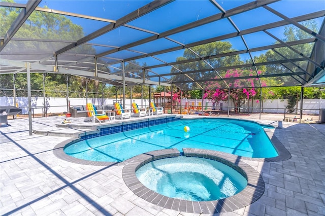 view of pool with glass enclosure, an in ground hot tub, and a patio area