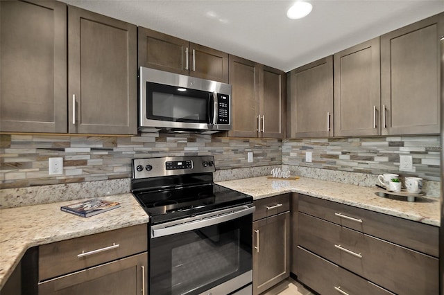 kitchen featuring backsplash, light stone countertops, dark brown cabinets, and stainless steel appliances