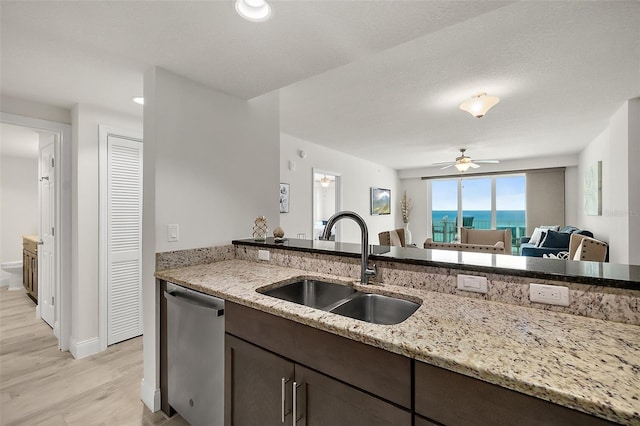 kitchen featuring light stone countertops, dark brown cabinetry, ceiling fan, sink, and dishwasher