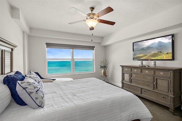 bedroom featuring dark colored carpet, ceiling fan, and a textured ceiling