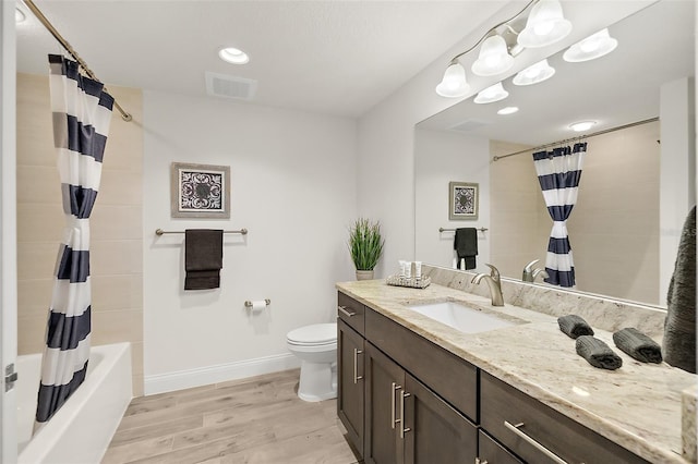 full bathroom featuring vanity, hardwood / wood-style flooring, shower / bathtub combination with curtain, a notable chandelier, and toilet