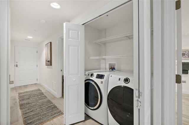 clothes washing area featuring light hardwood / wood-style flooring and washer and dryer