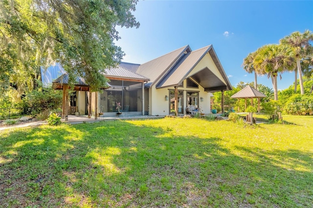 back of house with a lawn and a sunroom