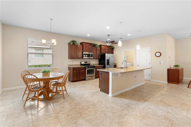 kitchen with sink, a kitchen breakfast bar, decorative light fixtures, a kitchen island with sink, and appliances with stainless steel finishes