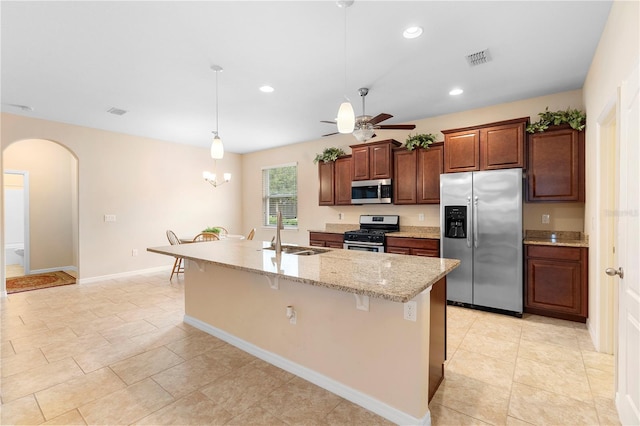 kitchen with pendant lighting, a kitchen island with sink, sink, appliances with stainless steel finishes, and a kitchen bar