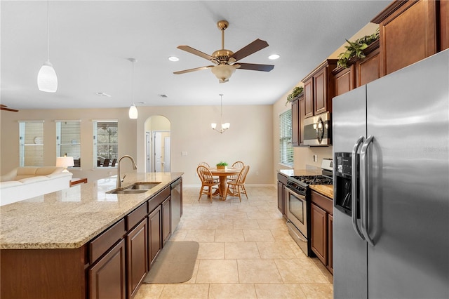 kitchen featuring an island with sink, stainless steel appliances, hanging light fixtures, and sink